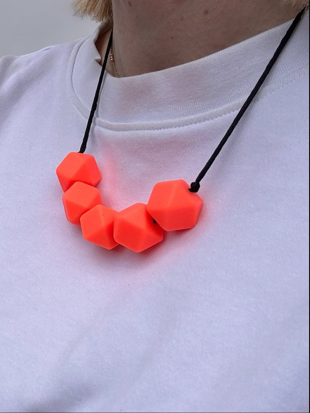 Person wearing a bright orange necklace on a plain background